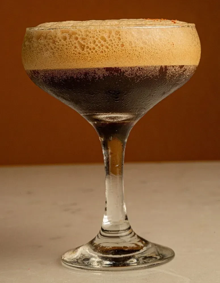 Dark drink with foam in a coupe glass.