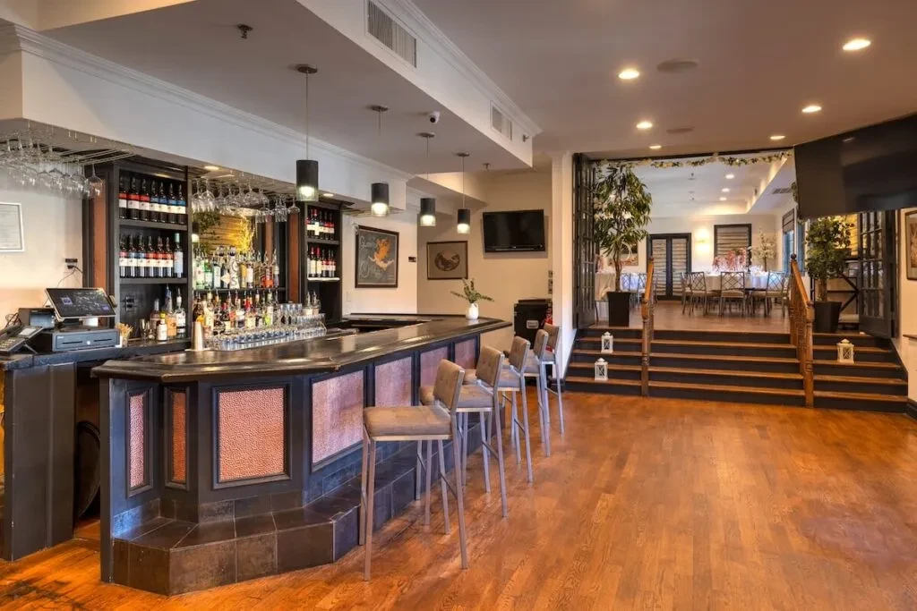 A bar with stools in a room with a hardwood floor and steps.