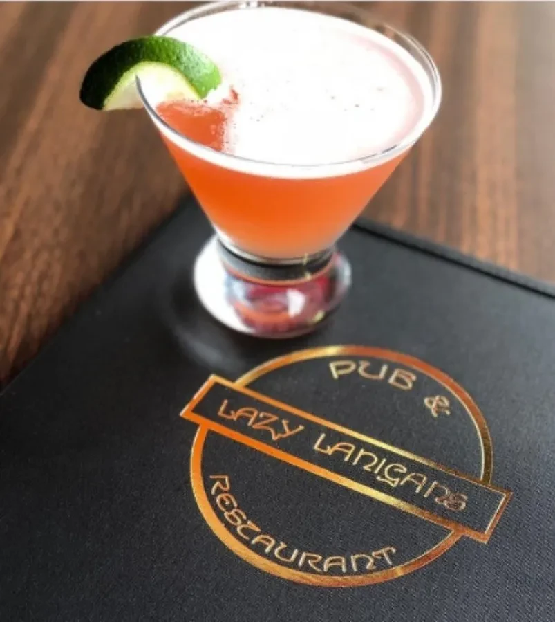 A cocktail with lime garnish on a Lazy Lanigans Pub & Restaurant menu.