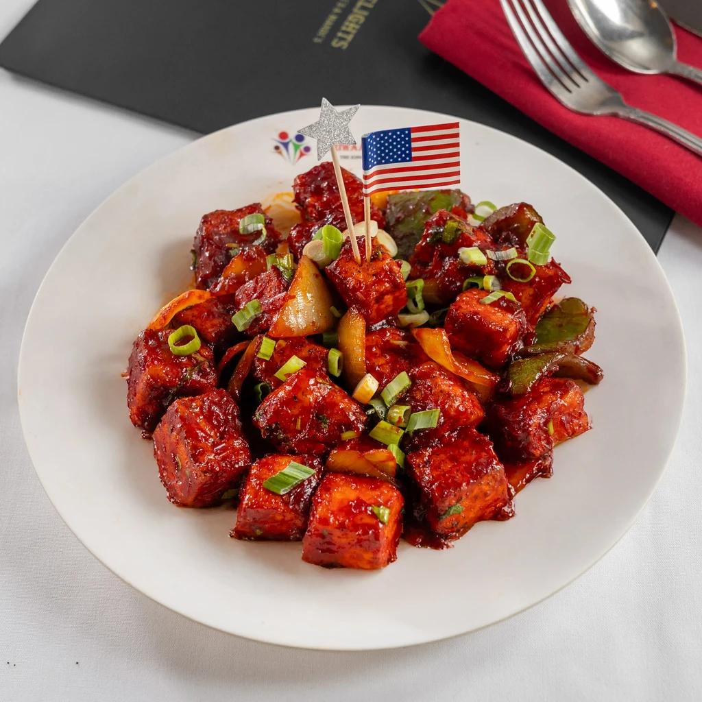 Plate of red-sauced food, green onions, bell peppers, US flag toothpick.