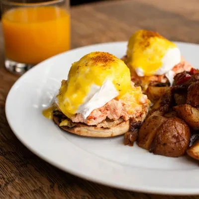 Eggs Benedict with roasted potatoes and orange juice.