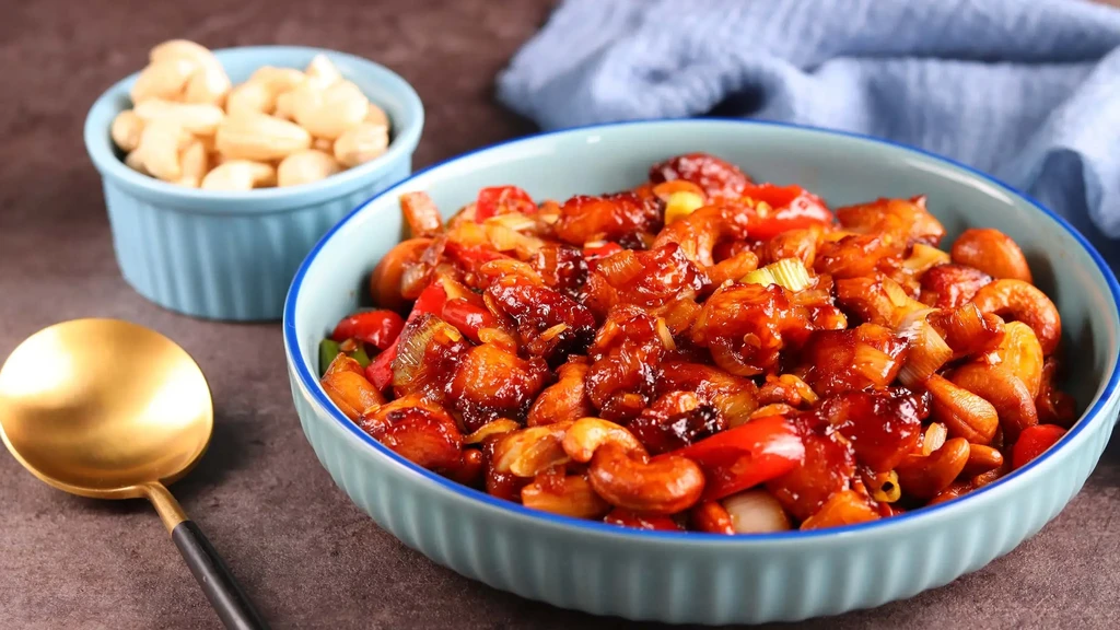 Cashew chicken stir-fry with red peppers in a light blue bowl.