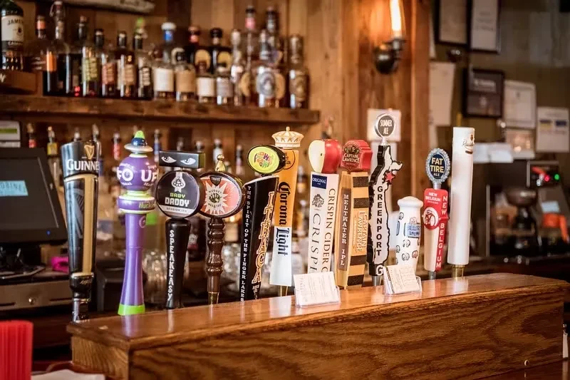 A row of beer taps on a wooden bar counter.
