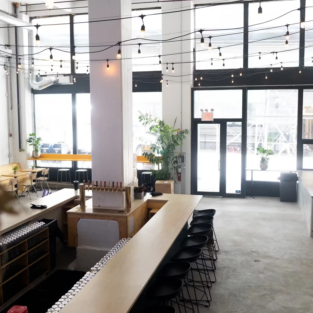 A brewery interior with beer taps, bar seating, and large windows.