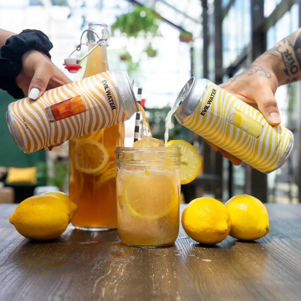 Two hands pour "Evil Water" iced tea and lemonade into a glass.