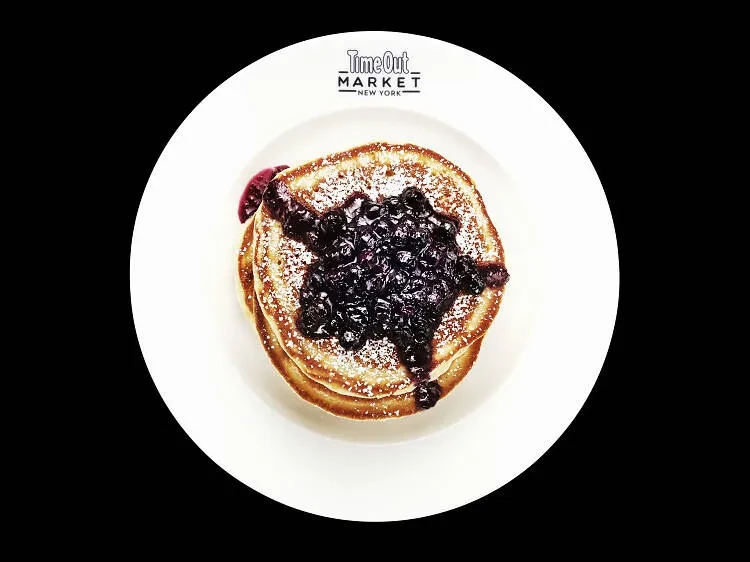 Pancakes with blueberries and powdered sugar on a white plate.