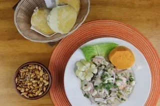 Ceviche with corn, sweet potato, fried corn, and bread on a table.