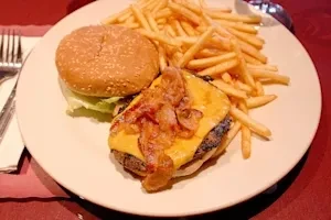 A cheeseburger with bacon, a bun, lettuce, and a side of french fries.