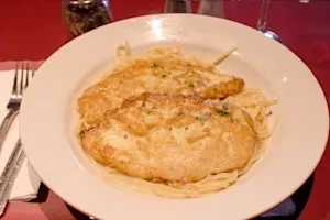 A white plate with chicken alfredo pasta and parsley garnish.
