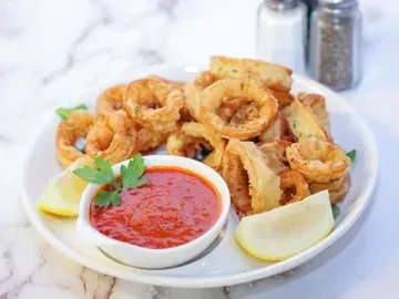 Fried calamari rings, lemon wedges, and a bowl of red sauce.