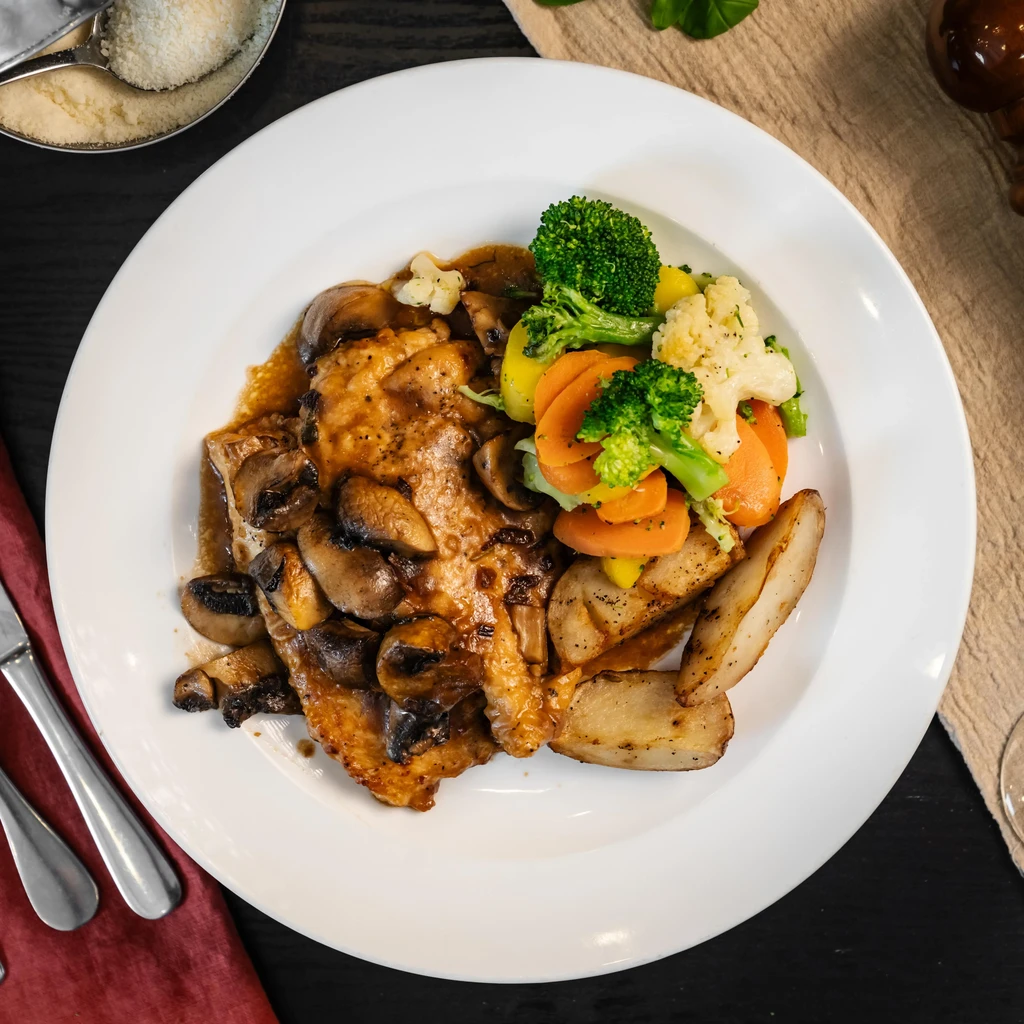 Mushroom chicken with steamed vegetables and roasted potatoes on a white plate.