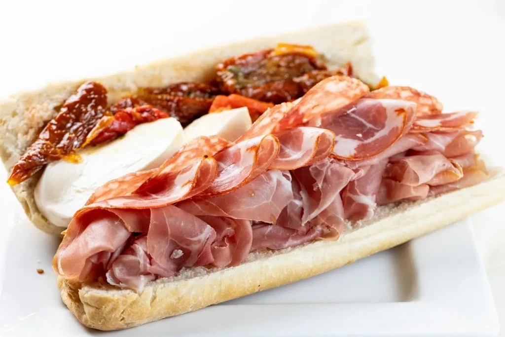 Sub sandwich with deli meats, mozzarella, and sun-dried tomatoes.