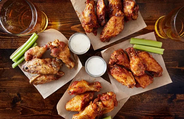 Chicken wings, celery sticks, and ranch dressing on a wooden table.