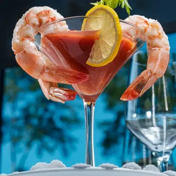 Shrimp cocktail with two prawns on the rim of a martini glass.