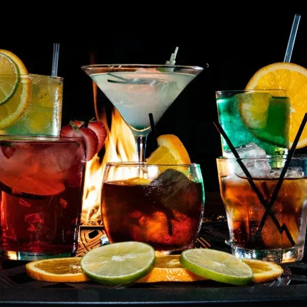Assortment of cocktails with fruit garnishes in front of a fire.
