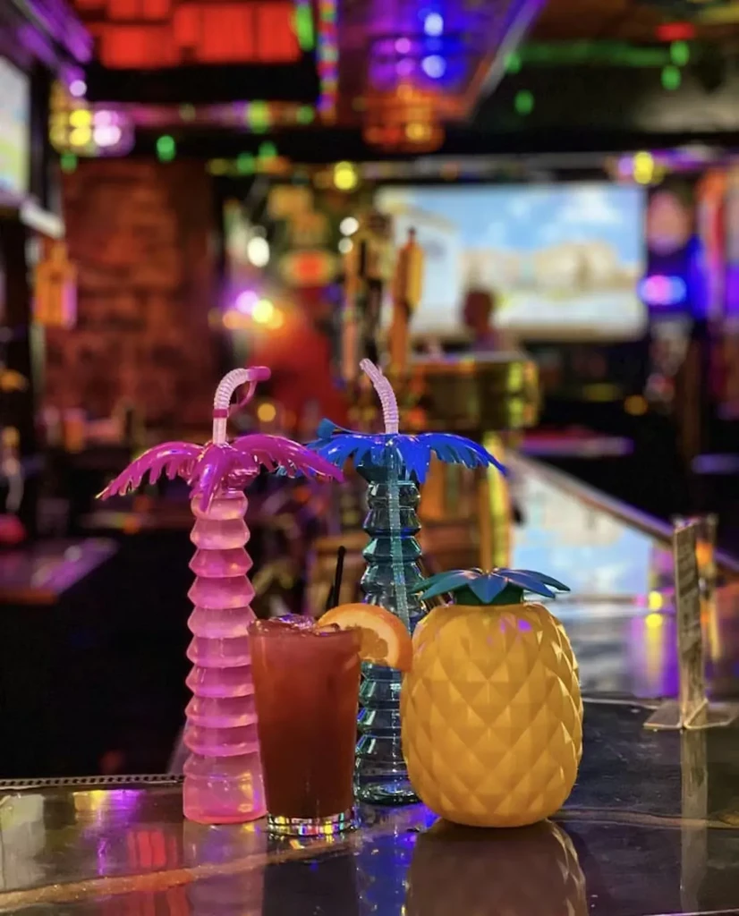 Tropical palm tree, red drink, and pineapple container on a bar.