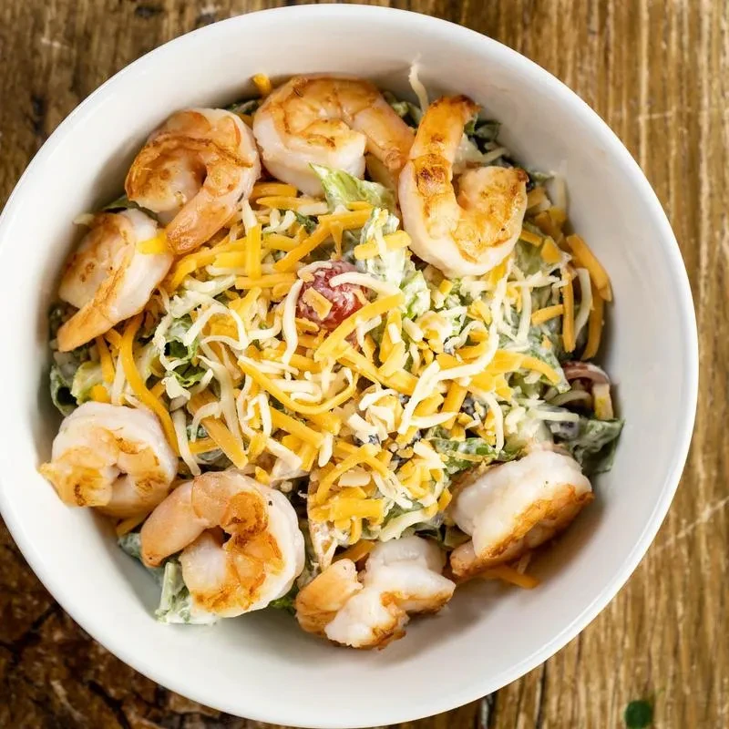 Overhead view of a shrimp salad in a white bowl.