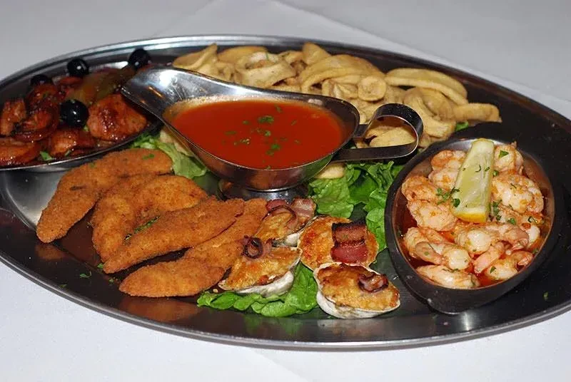 A large metal platter with various appetizers and dipping sauces.