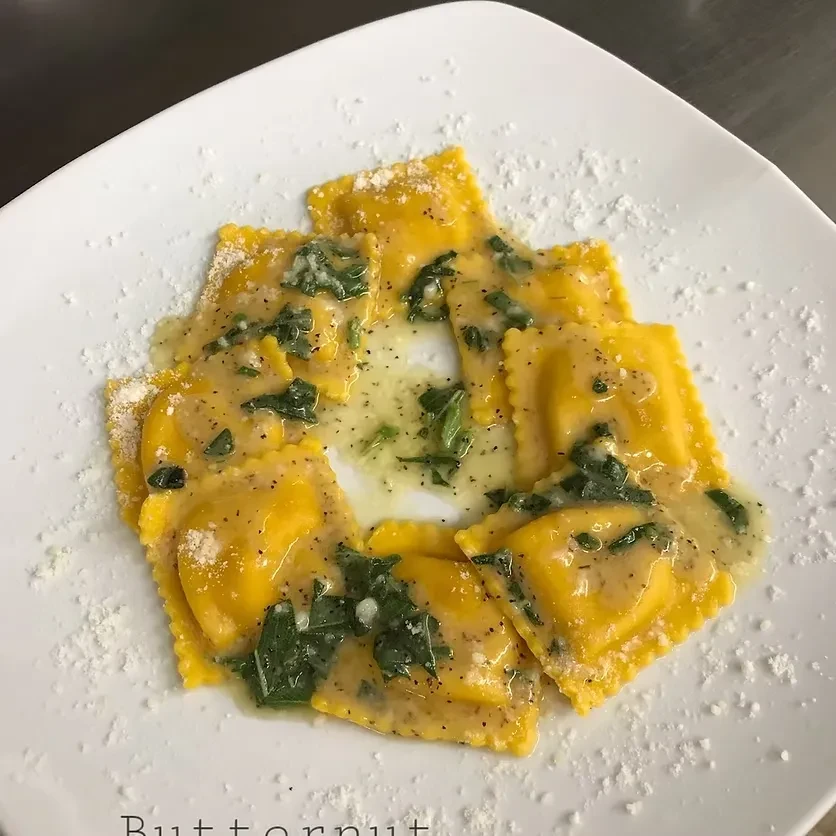 Butternut squash ravioli with a butter sage sauce, sprinkled with cheese.