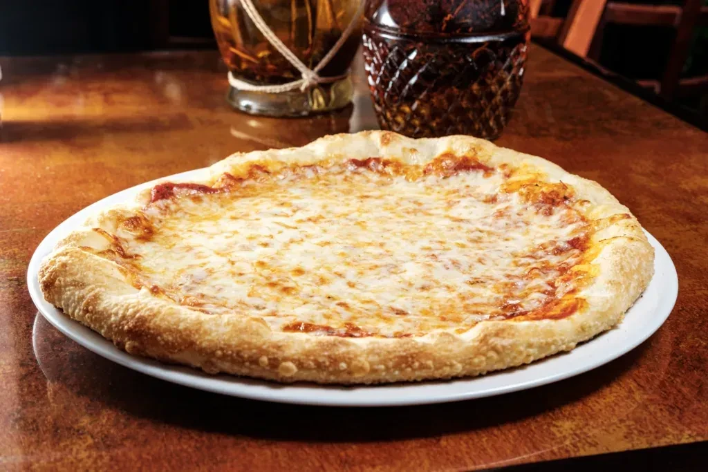 A large cheese pizza on a white plate.