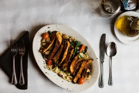 Overhead shot of a chicken pasta dish on a white table.