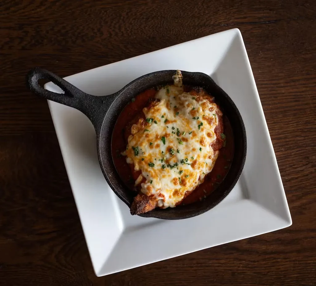 Chicken parmesan with melted cheese in a cast-iron skillet.