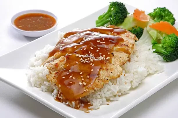 Teriyaki chicken, rice, and broccoli on a white rectangular plate.
