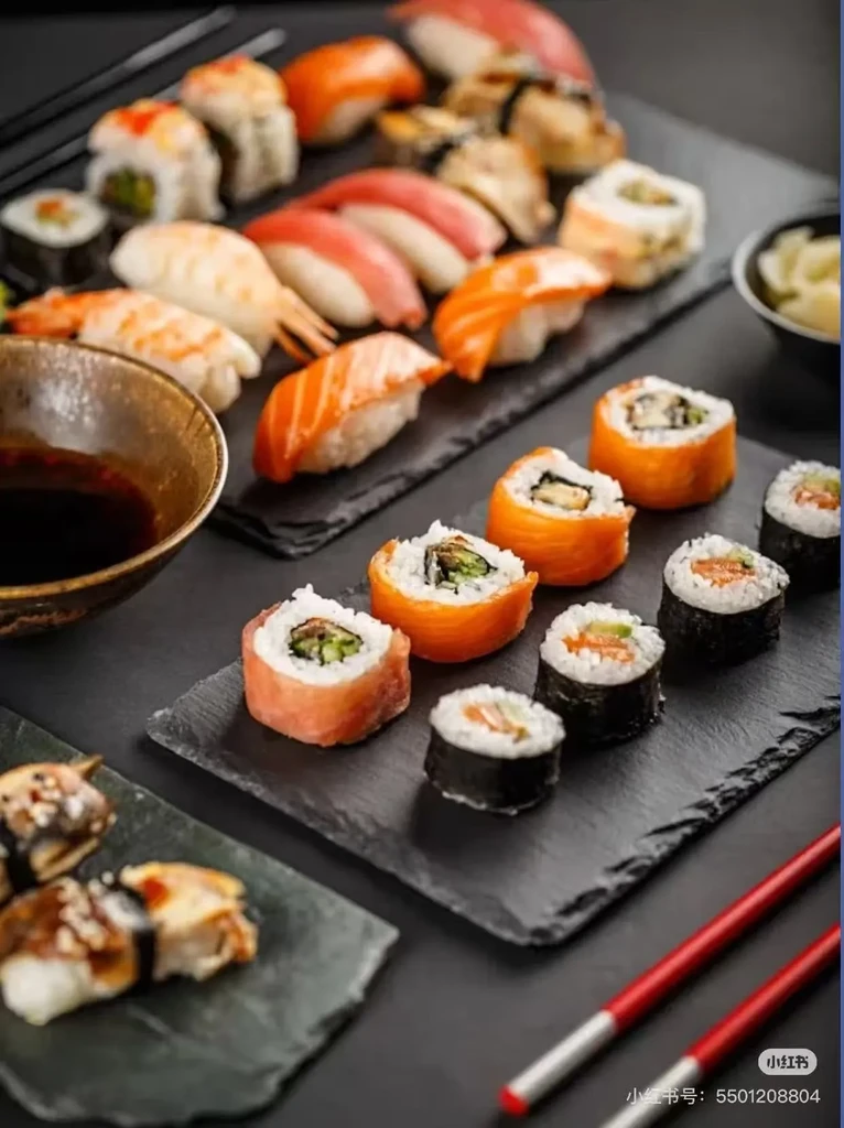 An assortment of fresh sushi, sashimi, and maki on black plates.