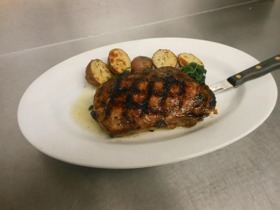 Grilled steak, roasted potatoes, and spinach on a white plate.