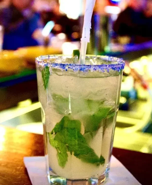 A close-up of a mint cocktail with a blue sugar-rimmed glass.