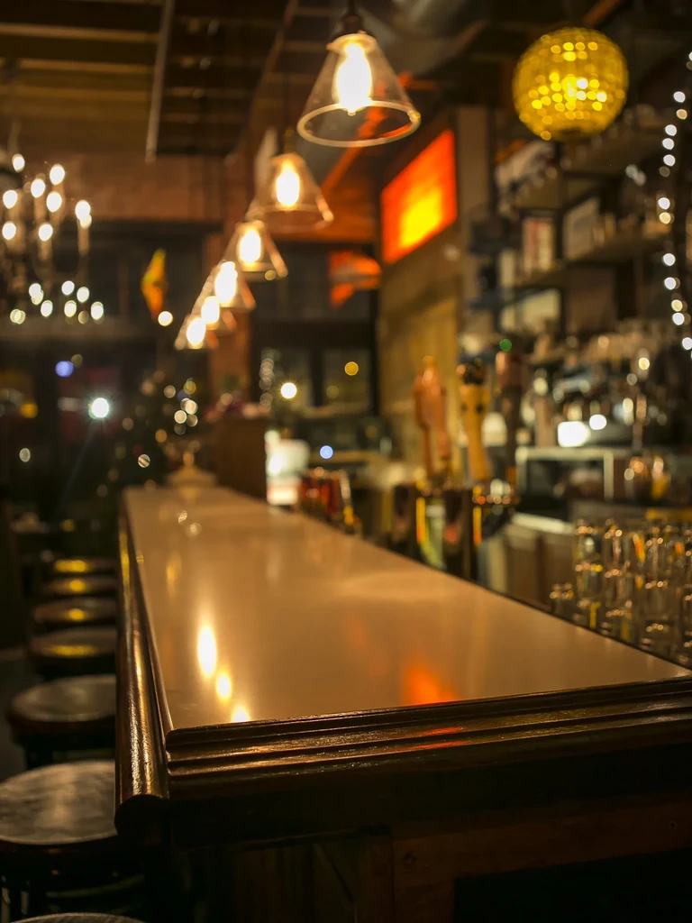 A long, empty bar with warm lights reflecting on its surface.