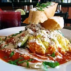 Chilaquiles with scrambled eggs, cheese, cilantro, and bread, served with a drink.
