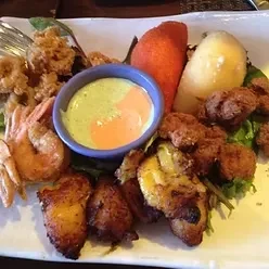 A platter of fried shrimp, plantains, pastry, and two dipping sauces.