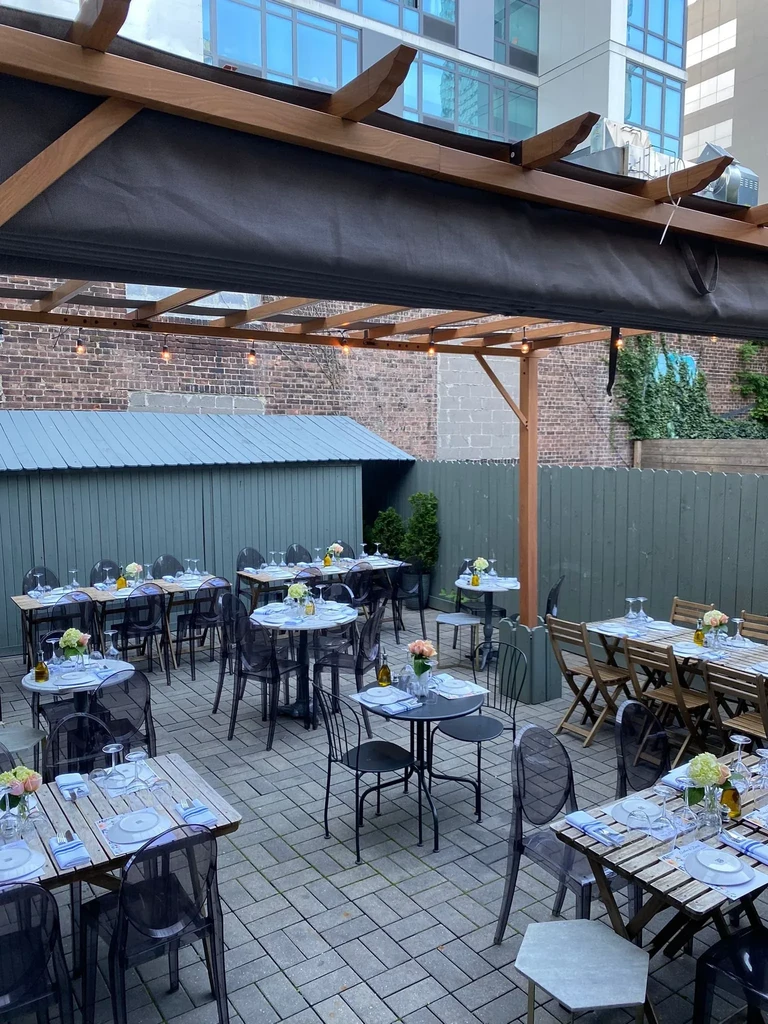 An empty outdoor restaurant patio with many tables under a pergola.