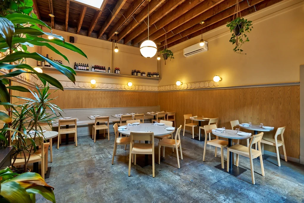 An empty modern restaurant with exposed ceiling beams and light wood paneling.