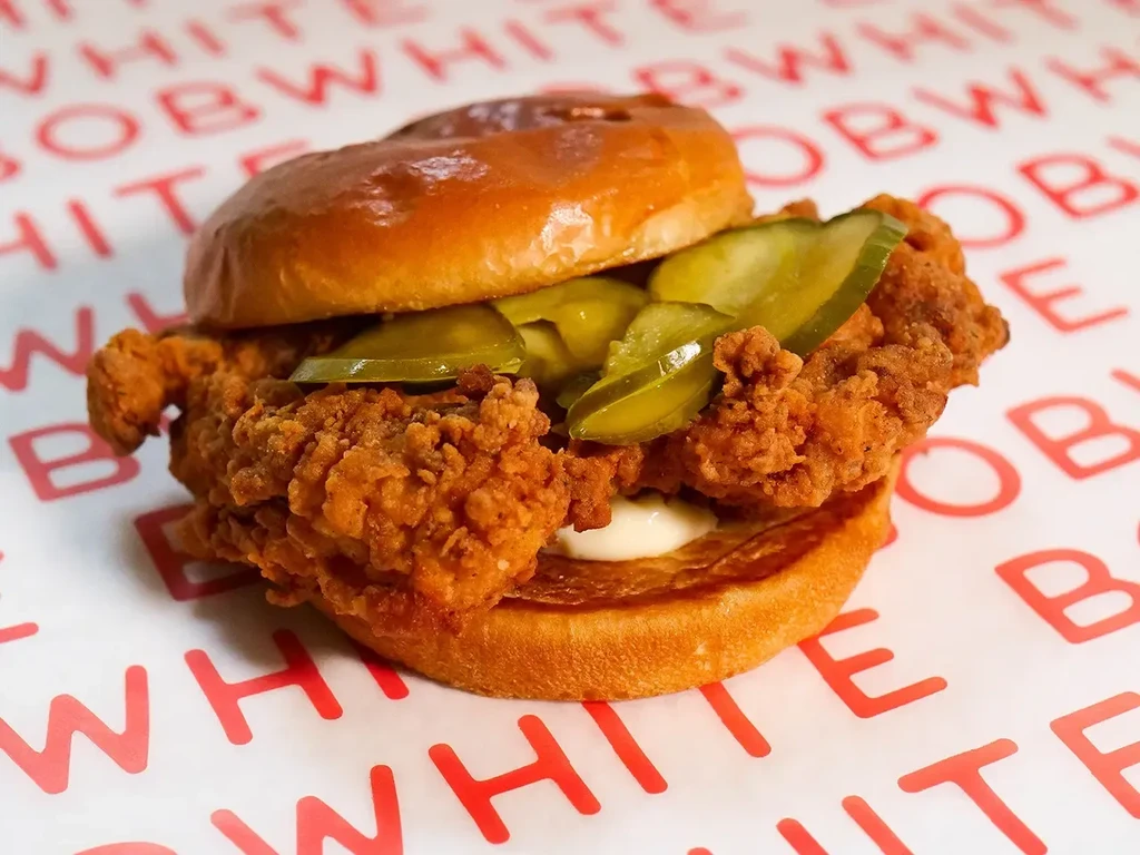 A fried chicken sandwich with pickles and mayo on a bun.
