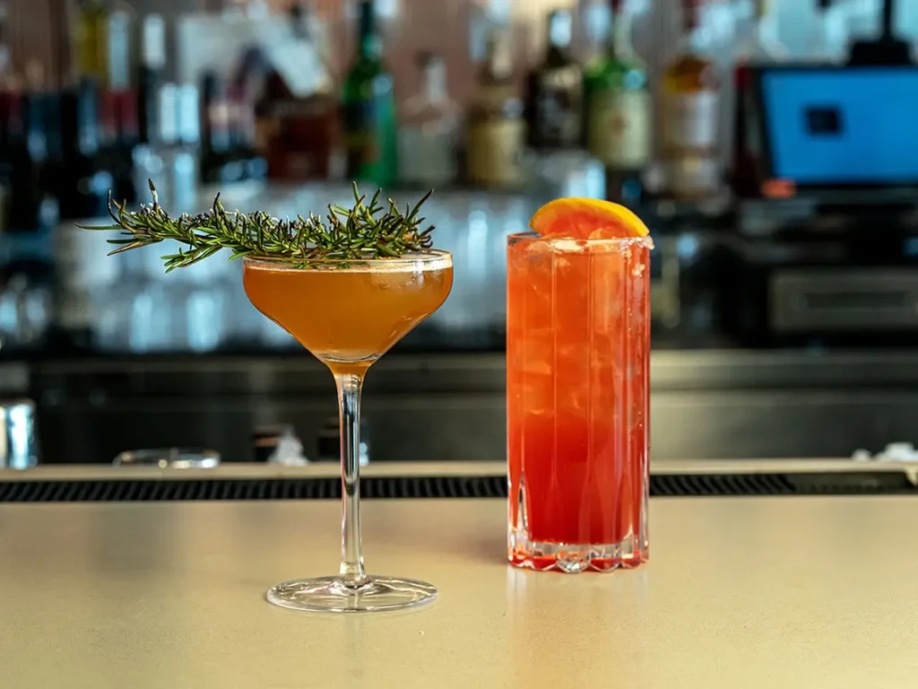 Two cocktails, one with rosemary, the other with a grapefruit slice.