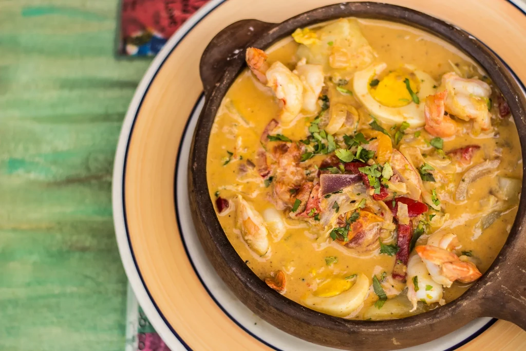 Overhead view of shrimp stew in a brown bowl.