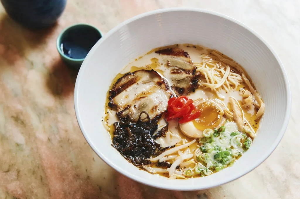 A bowl of ramen with pork belly, egg, and green onions.