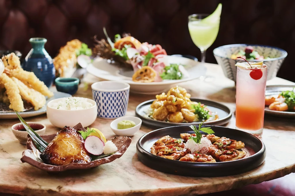 A table laden with Japanese dishes, cocktails, and drinks.