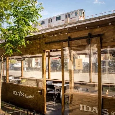Outdoor dining patio of Ida's Nearabout with a train passing overhead.