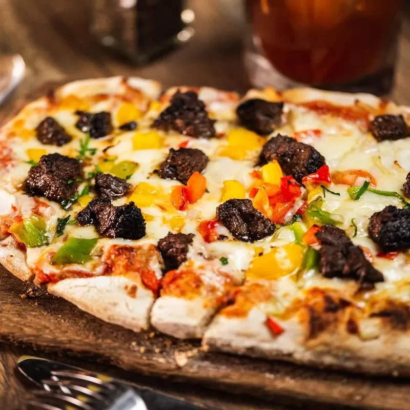 A rectangular pizza with meat, bell peppers, and melted cheese.