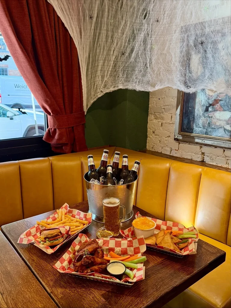 Restaurant table with food, beer, and Halloween spiderweb decorations.