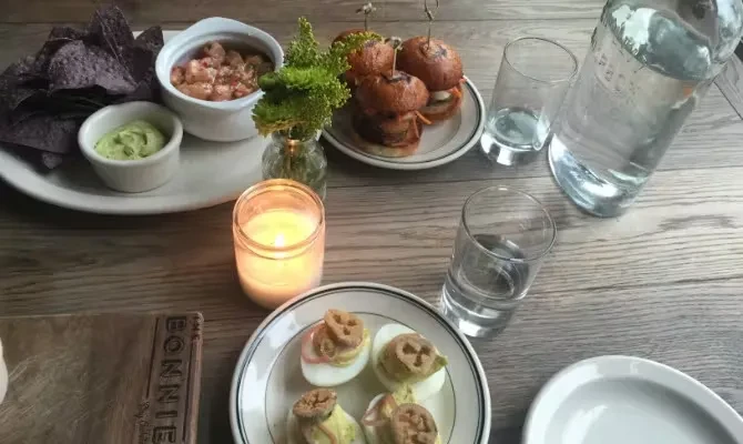 Overhead view of various appetizers and drinks on a wooden table.