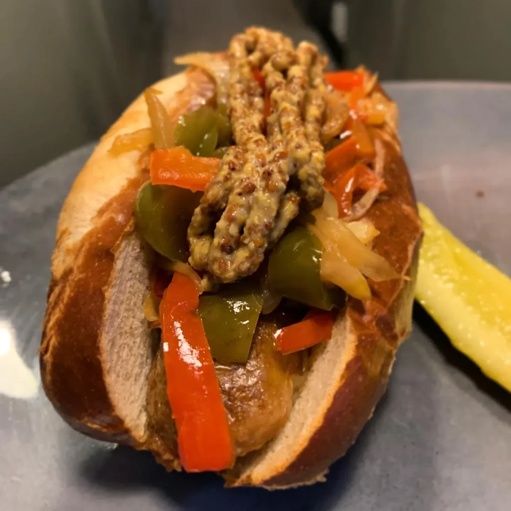 Sausage in pretzel bun, peppers, onions, whole grain mustard, and pickle.