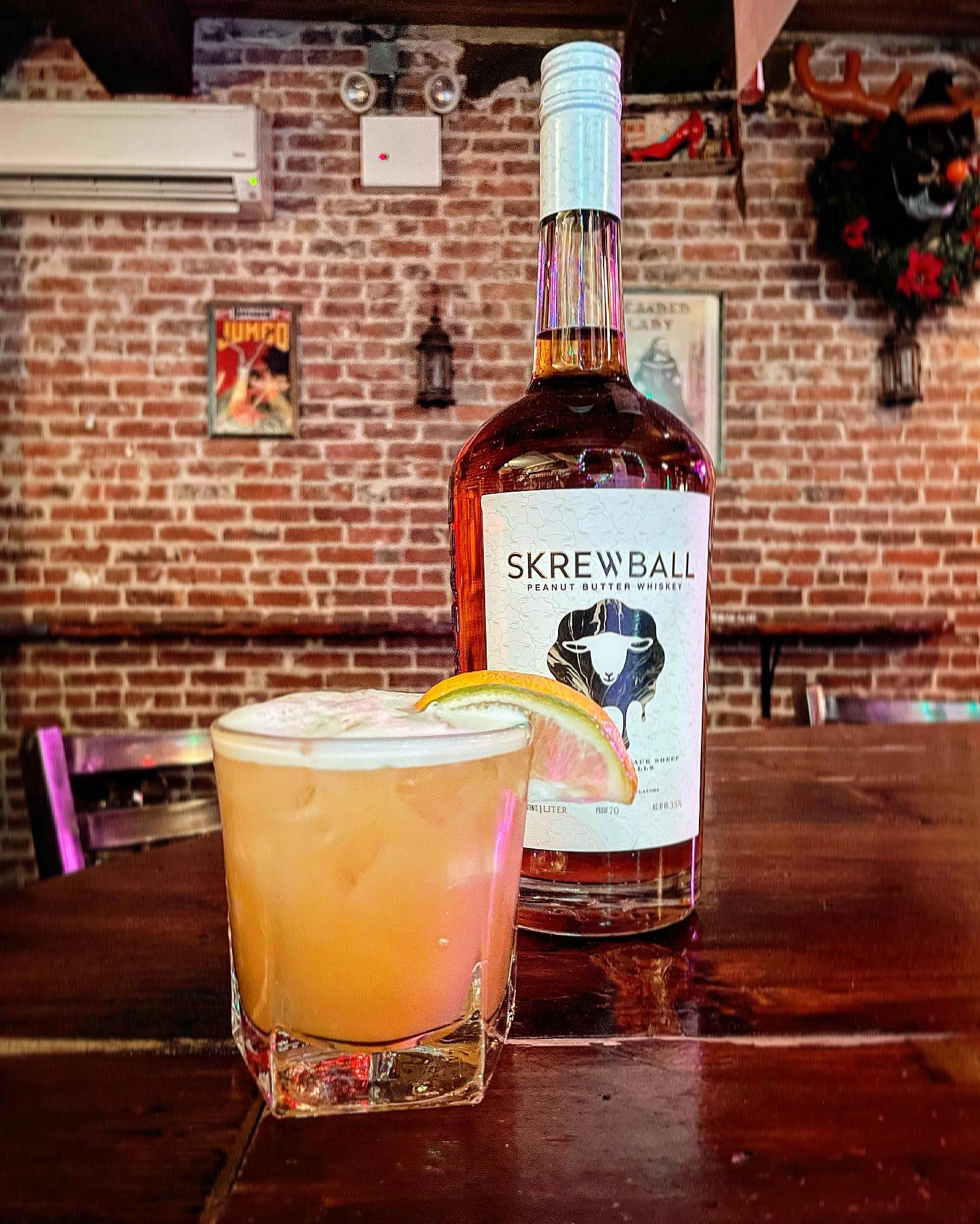 Bottle of Skrewball Peanut Butter Whiskey and a cocktail with citrus.