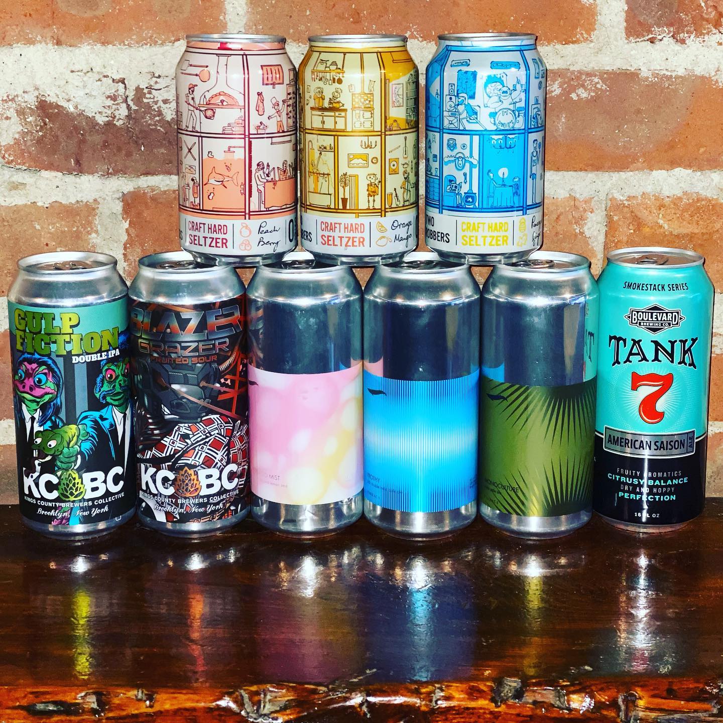 Two rows of colorful craft beer and seltzer cans on wood.