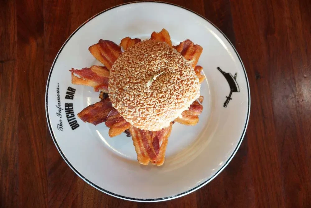 A sesame bun burger with bacon on a Butcher Bar plate.