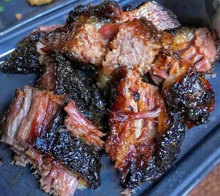 Close-up of pieces of charred, pulled pork or brisket on a tray.