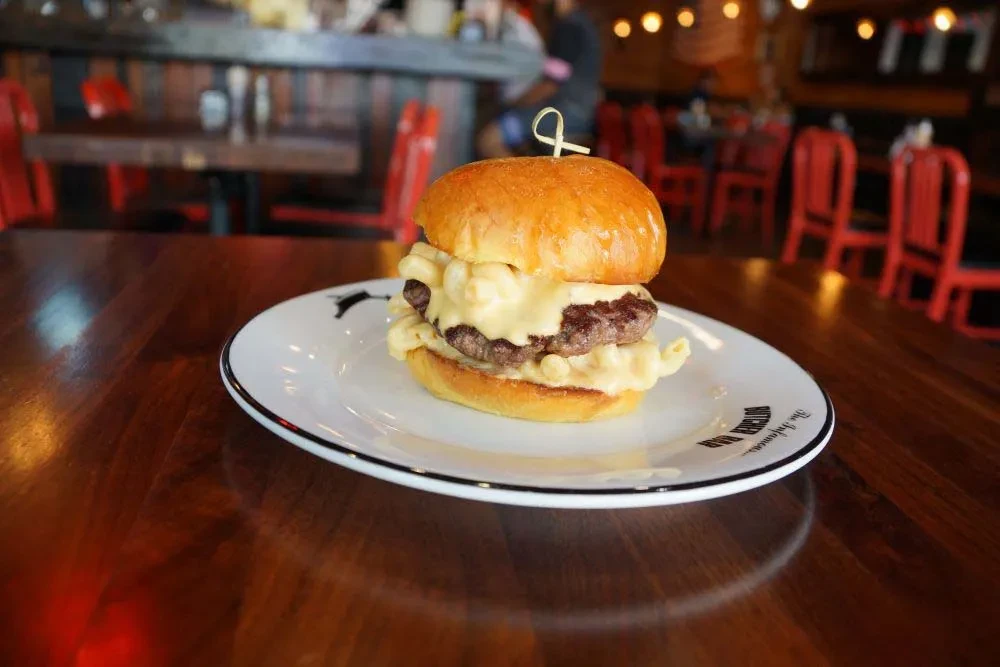 Mac and cheese burger on a white plate in a restaurant.